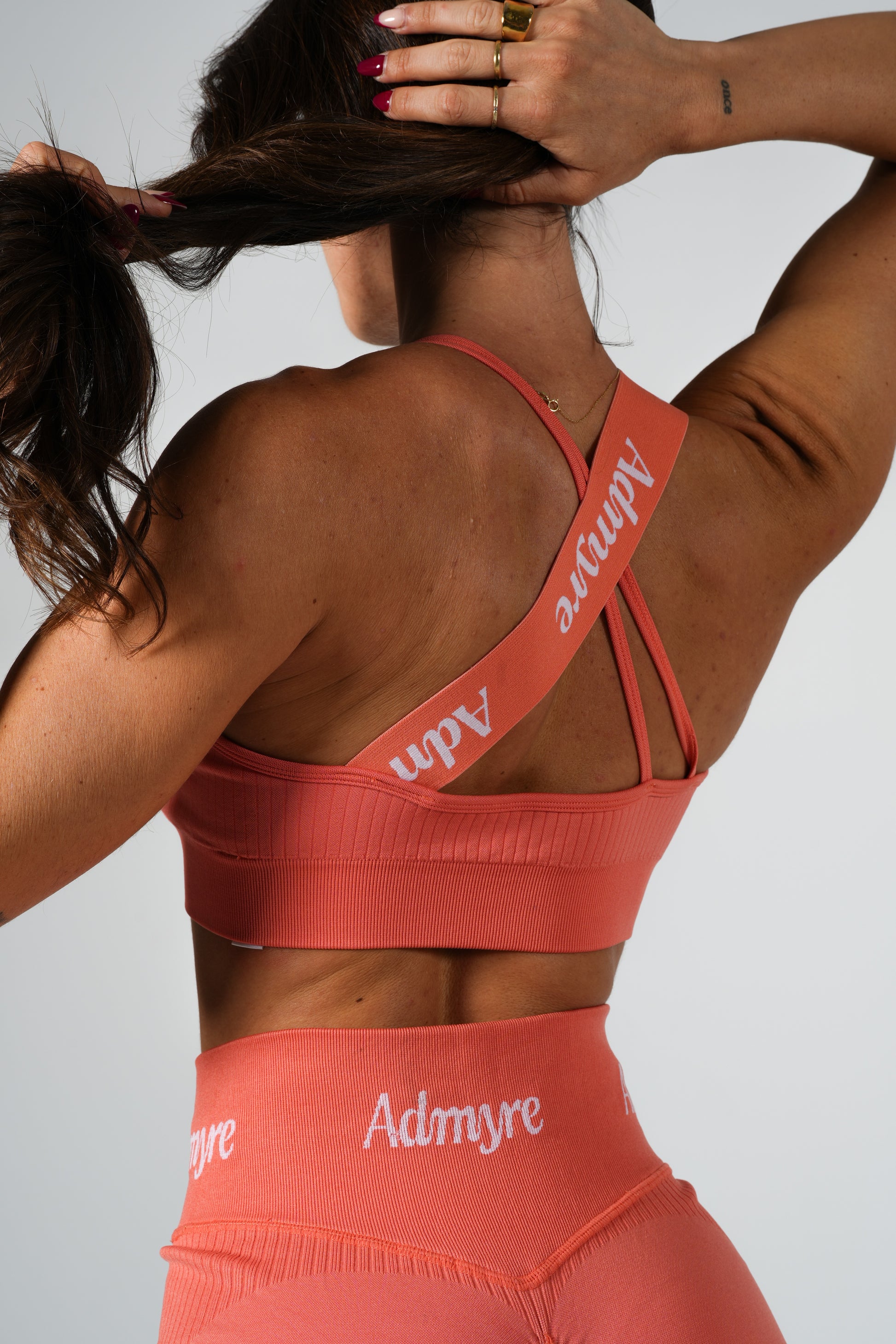 Lush Bra Admyre en coral, sujetador deportivo para mujer con sujeción firme y diseño estilizado. Perfecto para combinar rendimiento y confort