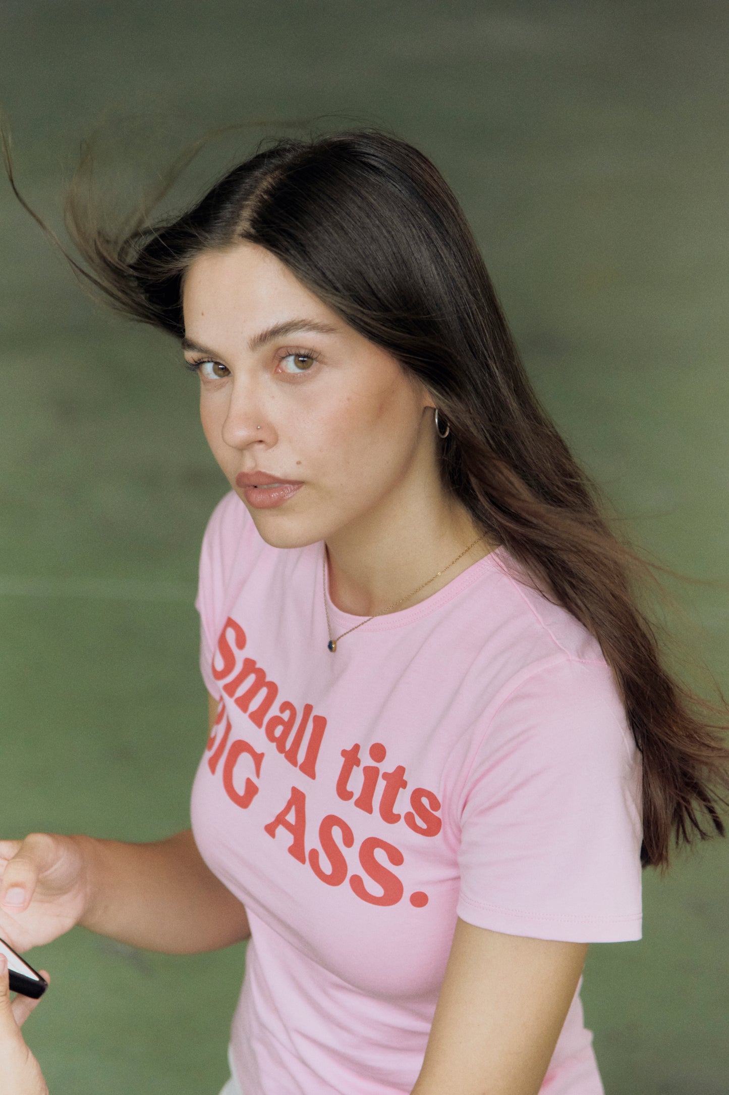 Camiseta rosa de Admyre Clothing para mujer con el mensaje 'Small Tits Big Ass'. Ideal para un look deportivo casual, esta camiseta destaca por su diseño atrevido y cómodo, perfecto para combinar con cualquier conjunto deportivo de mujer.